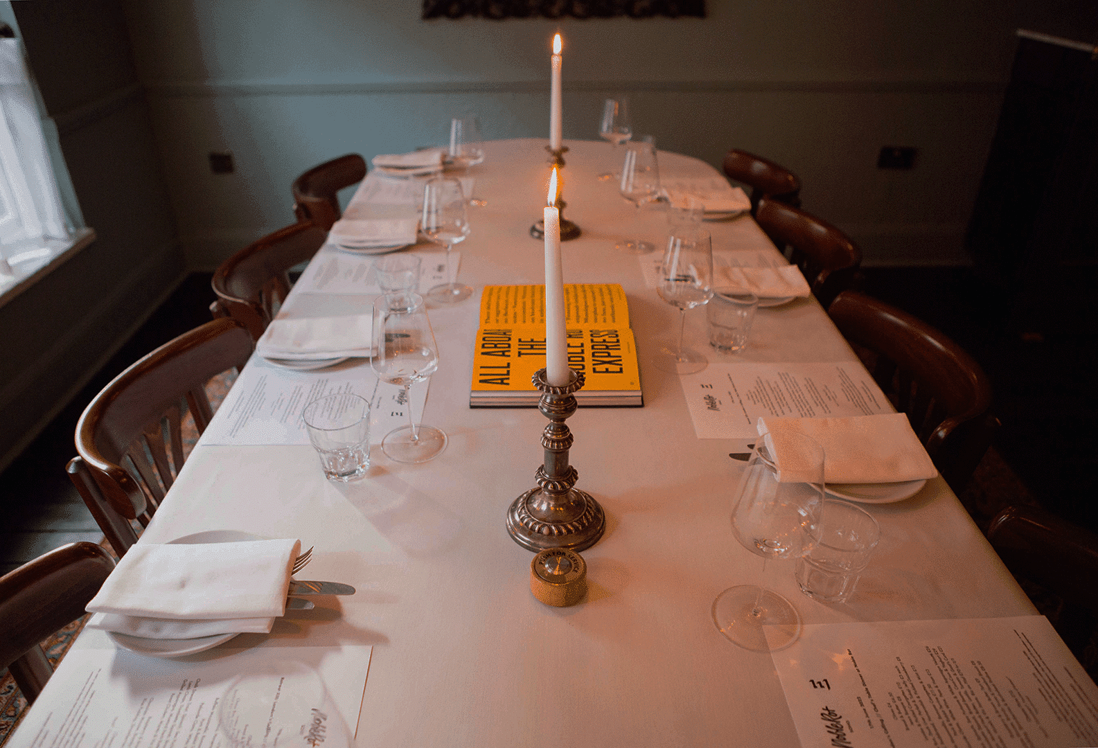 A candlelit dinner table set for a long supper